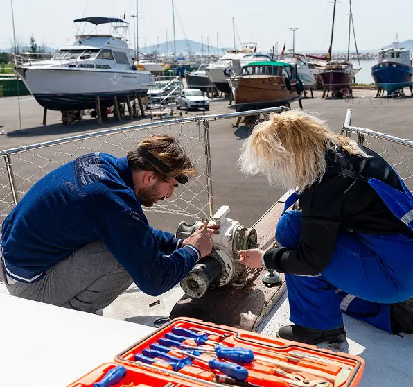 People repairing equipment on a boat deck.