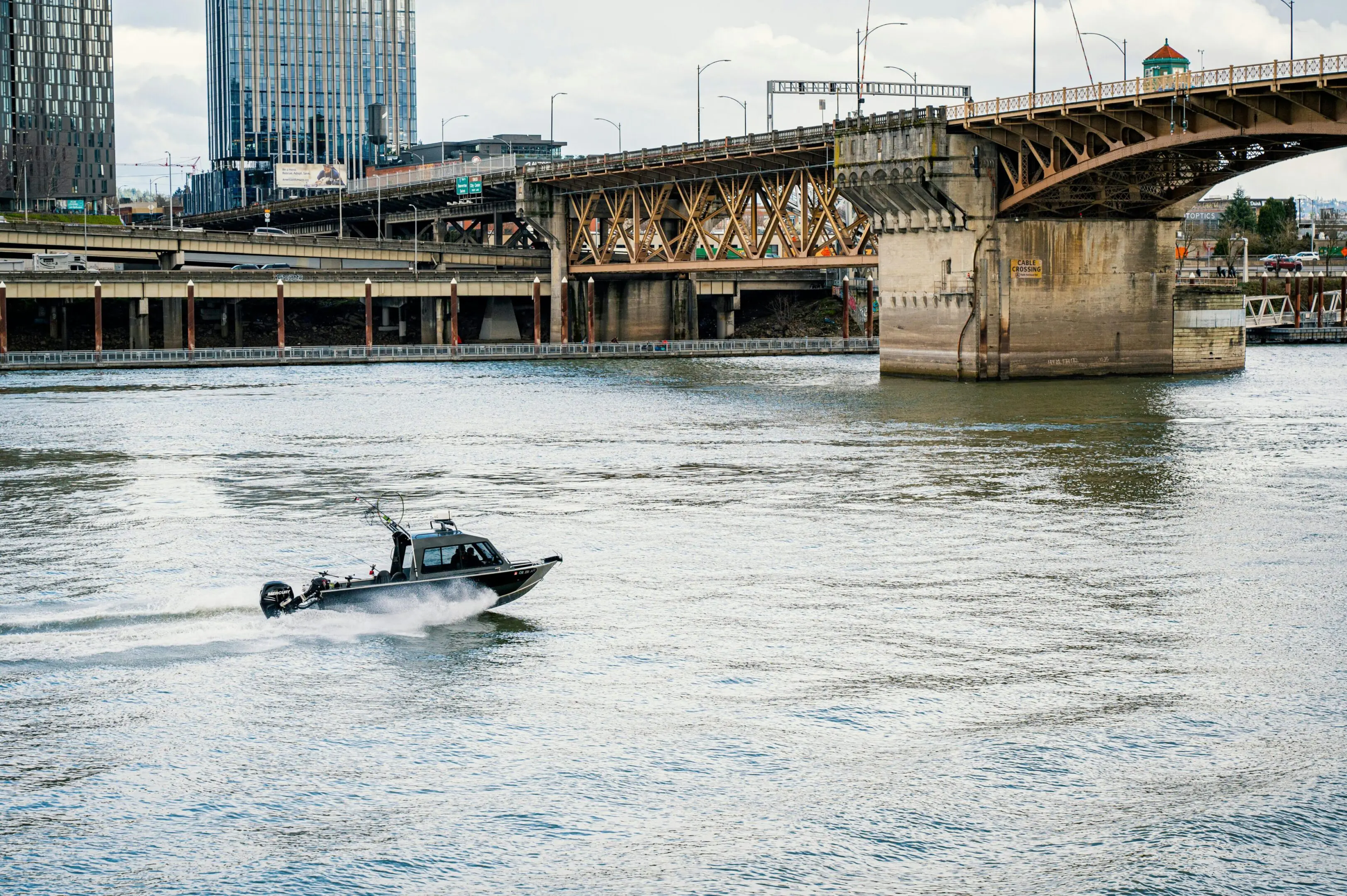 A police boat patrolling a river near a bridge in an urban area.