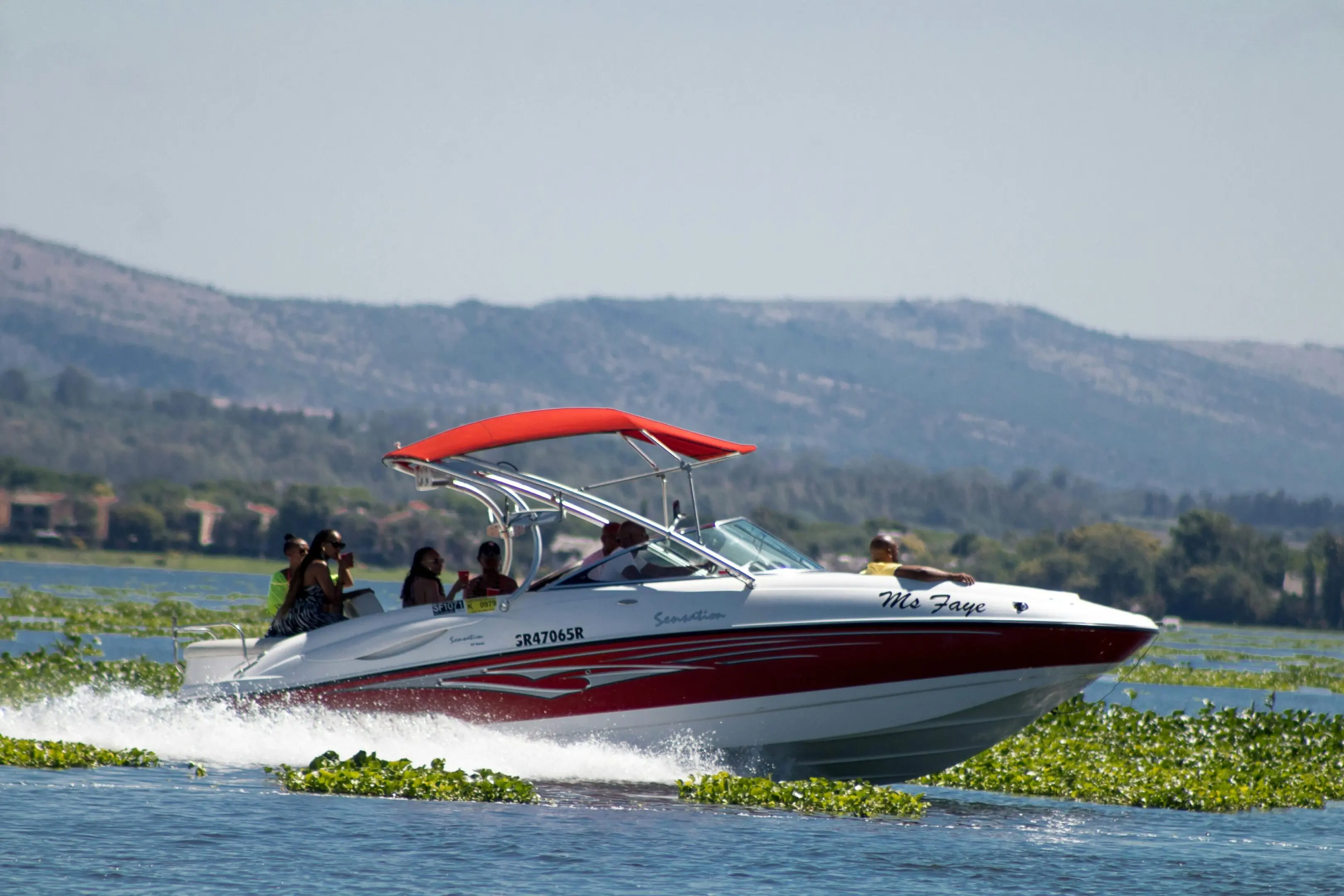 Speedboat cruising on a lake with hills in the background.